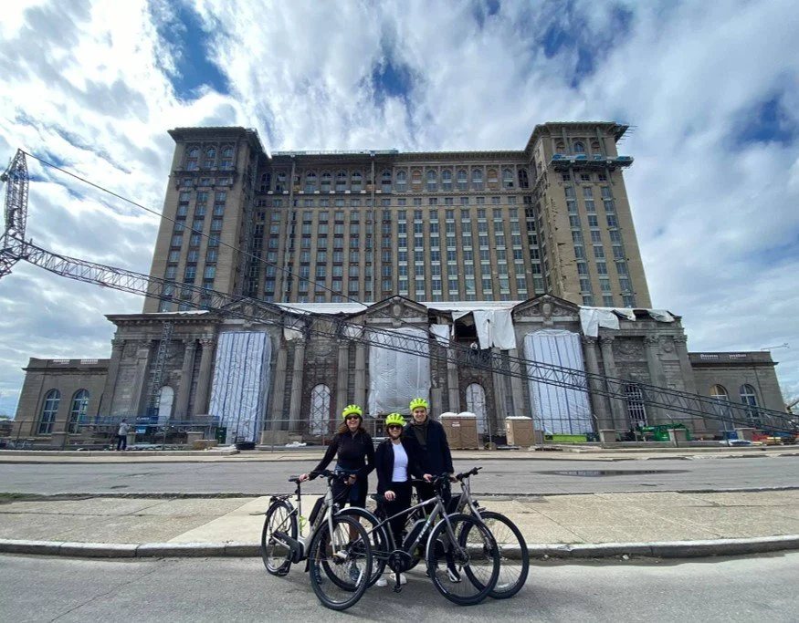 Two cyclists silhouetted in front of Michigan Central Station at sunset