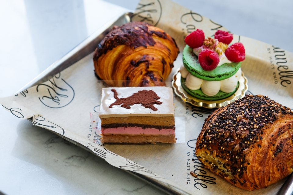 An assortment of donuts and pastries on a tray with a floral garnish