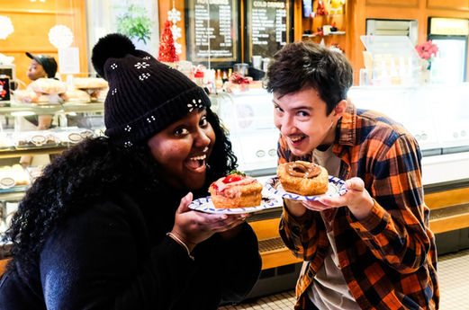 A couple smiles while eating donuts on the Detroit donut tour